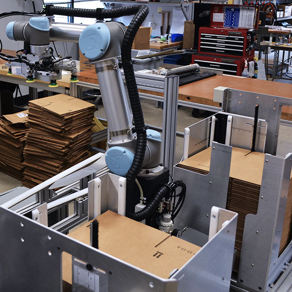 Case former cobot folding boxes in manufacturing process automation.